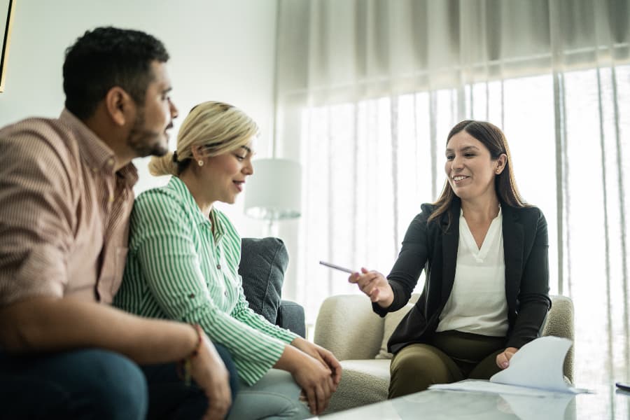 Couple meeting with real estate broker signing papers in home