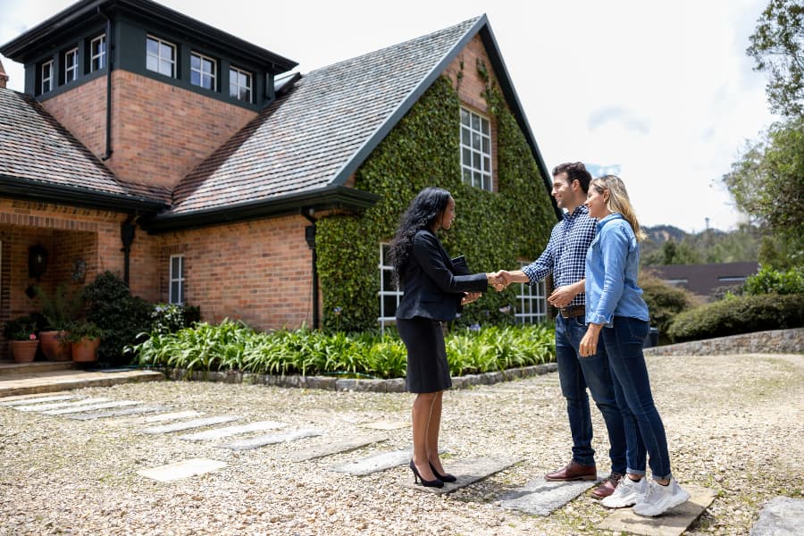 Real estate agent greeting couple for house showing